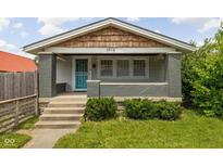 Charming home featuring a covered front porch with painted brick pillars and a vibrant turquoise storm door at 3916 E 10Th St, Indianapolis, IN 46201