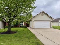Charming home featuring an attached two-car garage, brick facade, manicured lawn and mature shade tree at 509 Woodberry Dr, Danville, IN 46122