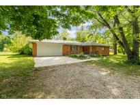 Charming brick home featuring an attached garage, front yard foliage and gravel driveway at 6498 N County Road 475 E, Pittsboro, IN 46167