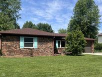 Brick home with beautiful lawn and landscaping features a brown roof and blue shutters at 7824 Hearthstone Way, Indianapolis, IN 46227