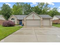 Charming brick home boasts a well-manicured lawn and attached three car garage at 1124 Enchanted View Dr, Mooresville, IN 46158