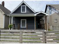 Charming home with dark siding, a quaint front porch, and a decorative fence adds to its curb appeal at 1518 S Talbott St, Indianapolis, IN 46225