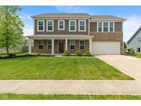 Two-story home boasts manicured lawn, brick accents, covered porch, and an attached two car garage at 2626 Solidago Dr, Plainfield, IN 46168