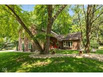 Charming home featuring a brick and wood facade, a red door, and mature trees in a landscaped front yard at 3479 Sugar Loaf Ct, Carmel, IN 46033