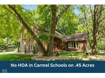 Charming two-story brick home with a landscaped yard and mature trees, offering a serene and private setting at 3479 Sugar Loaf Ct, Carmel, IN 46033