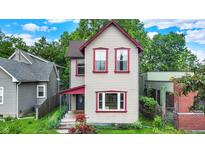 Charming two-story home with light siding, red trim, and lush landscaping in a residential neighborhood at 514 Dorman St, Indianapolis, IN 46202