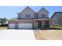 Two-story home featuring a three-car garage, gray siding, brick accents, and a covered front porch at 5517 Sienna Ct, Brownsburg, IN 46112