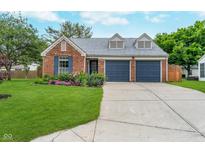 Charming brick home featuring a two-car garage, well-manicured lawn, and colorful flower beds at 6789 Passage Cir, Indianapolis, IN 46250