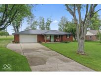 Charming red brick home with a metal roof, green door, and a well-maintained front yard at 679 Bark Dr, Anderson, IN 46011