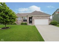 Charming brick home featuring a well-maintained lawn, mature tree, and two-car garage at 7724 Dunleer Dr, Brownsburg, IN 46112