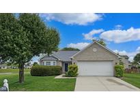 Charming single-story home featuring a well-manicured lawn, mature trees, and attached two-car garage at 8121 Sand Ridge Cir, Indianapolis, IN 46237