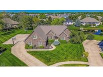 Aerial view of brick home with pond, basketball court, green lawn, and mature trees at 7093 Republic Ln, Indianapolis, IN 46259