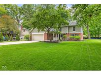 Beautiful two-story home featuring a brick facade, attached garage, and a spacious green lawn at 8934 Pinyon Ct, Indianapolis, IN 46260
