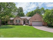 Charming brick home featuring a manicured front lawn, mature trees, and an attached two-car garage at 10759 Sawgrass Dr, Fishers, IN 46037