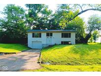 Charming split-level home featuring a front-facing garage and lush green landscaping in a peaceful neighborhood at 1325 Northcrest Dr, Anderson, IN 46012