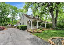 Charming home featuring a welcoming front porch, lush landscaping, and a spacious driveway at 1725 W 53Rd St, Indianapolis, IN 46228