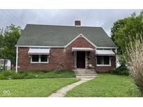 Charming brick home featuring a peaked roof, awnings, and a small front garden with a traditional-style entrance at 230 E Poplar St, Danville, IN 46122