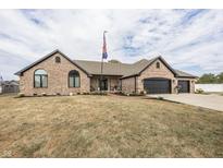 Charming brick home featuring an attached three-car garage, well-manicured lawn and flagpole at 28 Patriot Ct, Greenfield, IN 46140
