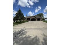 Brick home with a large driveway and an attached two-car garage, framed by a green lawn and mature trees under a blue sky at 28 Patriot Ct, Greenfield, IN 46140