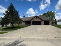 Charming brick home featuring a spacious driveway and a three-car garage, perfect for a growing Gathering at 28 Patriot Ct, Greenfield, IN 46140