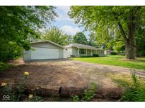 Charming ranch-style home with detached garage and mature trees in a serene, landscaped setting at 5160 N High School Rd, Indianapolis, IN 46254