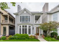 Charming two-story home with gray siding, bay window, front porch, and professionally landscaped yard at 626 N Senate Ave, Indianapolis, IN 46202