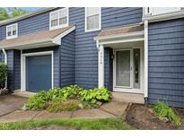 Inviting townhouse with a blue exterior, well-kept landscaping, and attached garage at 7510 Harbour, Indianapolis, IN 46240