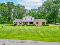 Well-maintained home with mature trees and an expansive green lawn at 8772 W Evergreen Dr, Columbus, IN 47201