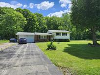 View of the front yard with a mix of brick and vinyl siding along with a long driveway leading up to the garage at 10307 Orchard Park S Dr, Carmel, IN 46280
