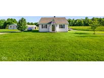 Charming one-story house featuring a well-maintained lawn, an exterior propane tank, and supplemental storage structures at 10758 W State Road 142, Quincy, IN 47456