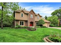 Charming two-story home featuring a brick facade, well-manicured lawn, and a bright red front door at 11469 Woodview Ct, Fishers, IN 46038
