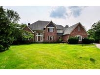 Stately brick home features an expansive green lawn, mature trees, and an inviting front entrance at 12854 Northants Cir, Carmel, IN 46032