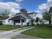 Charming two-story home featuring a front porch, well-maintained lawn, and a separate garage at 207 E Plum St, Anderson, IN 46012