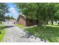 Quaint brick home with a large tree in the front yard and an oversized garage at 25420 Jerkwater Rd, Sheridan, IN 46069