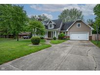 Charming home boasts a well-manicured lawn, inviting porch, and an attached two-car garage at 4013 Hillendale Dr, Greenwood, IN 46142