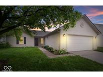 Charming single-story home featuring a two-car garage, well-kept lawn, and tasteful landscaping at sunset at 6011 Twyckenham Dr, Indianapolis, IN 46236