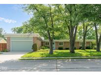 Charming single-story home featuring stone accents, a well-manicured lawn, mature trees, and a two-car garage at 650 W Main St, Carmel, IN 46032