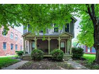 Charming two-story home featuring a covered porch and landscaped front yard with mature trees at 925 Fayette St, Indianapolis, IN 46202