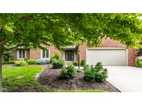 Charming brick home featuring an attached garage, beautifully landscaped front yard, and a covered entrance at 9445 Moorings Blvd, Indianapolis, IN 46256