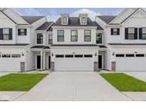 A townhome with white siding, black accents, and a two car garage, showcasing modern curb appeal at 9741 Oleander Dr, Fishers, IN 46250