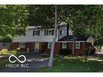 Charming two-story home featuring a brick facade, black shutters, well-manicured lawn, and mature trees at 1238 N 650 W, Anderson, IN 46011