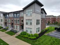 Modern townhome with brick and stone facade, manicured landscaping, and a welcoming entrance at 12908 Grand Blvd, Carmel, IN 46032