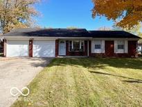 Charming single-story brick home featuring a two-car garage, manicured lawn, and inviting front porch at 1308 N Main St, Lapel, IN 46051