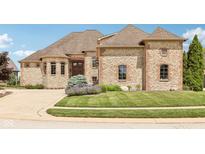 Stunning stone and brick home featuring manicured lawn, mature landscaping, and a charming covered entryway at 16332 Valhalla Dr, Noblesville, IN 46060