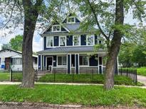Charming two-story blue home with white trim, well-manicured lawn and black metal fence at 201 N Tacoma Ave, Indianapolis, IN 46201