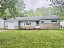 Charming single-story home with a stone facade and attached garage, surrounded by lush greenery at 3325 Canaday Dr, Anderson, IN 46013