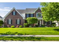 Beautiful brick two-story home with manicured lawn, decorative trees, and black shutters at 6649 Braemar S Ave, Noblesville, IN 46062