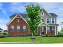 Charming two-story home featuring a brick facade, a manicured lawn, and lush landscaping at 7046 Allegiance Ct, Indianapolis, IN 46259