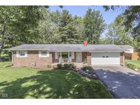 Charming brick ranch-style home with an attached garage, landscaped yard, and mature trees at 8246 S Franklin Rd, Indianapolis, IN 46259