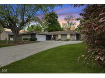 Charming single-story home with stone accents, a spacious driveway, and lush green lawn at 1311 N Eaton Ave, Indianapolis, IN 46219